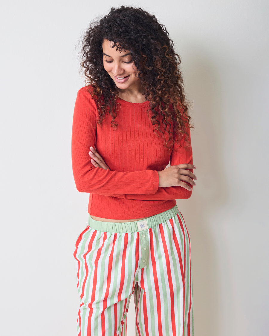 Model wearing Elf Stripes petite Nola pajama pants with vertical sage and cherry stripes, shown in a three-quarter front view.