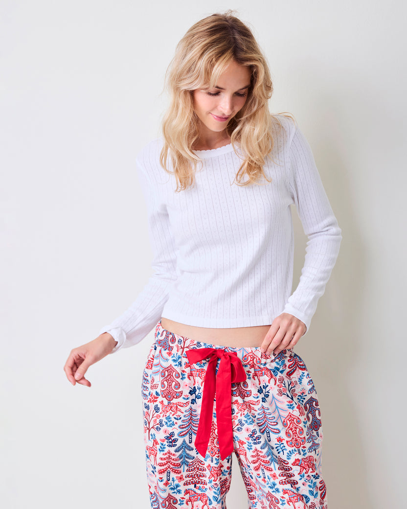 Person wearing wide-leg patterned pants with red-and-blue motifs and a red waist tie.
