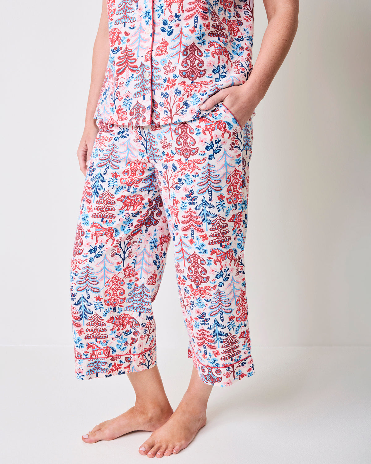 Close view of the cropped pajama pants with side pockets and a red and blue forest-inspired print.
