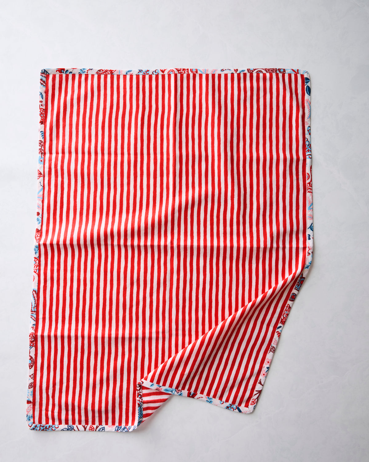 Tea towel showing the red-and-white striped reverse side with a patterned border.