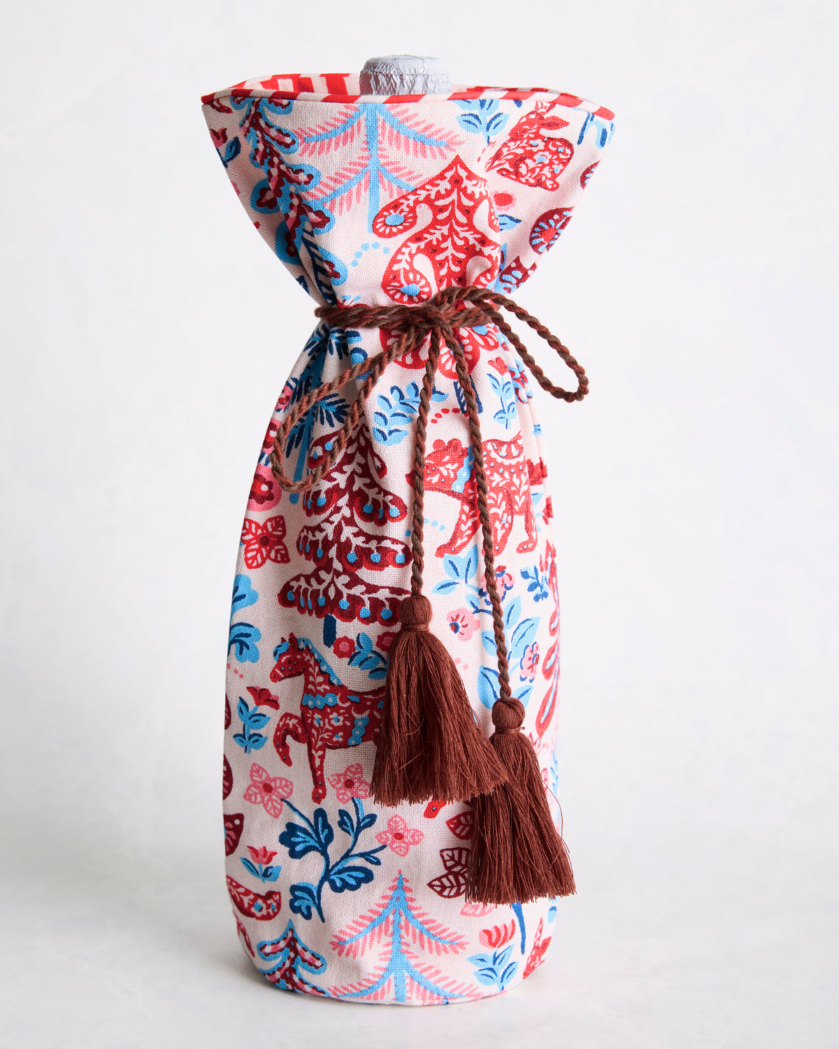 Printed wine bag standing upright with a bottle visible at the top and brown braided drawstring ties with tassels.