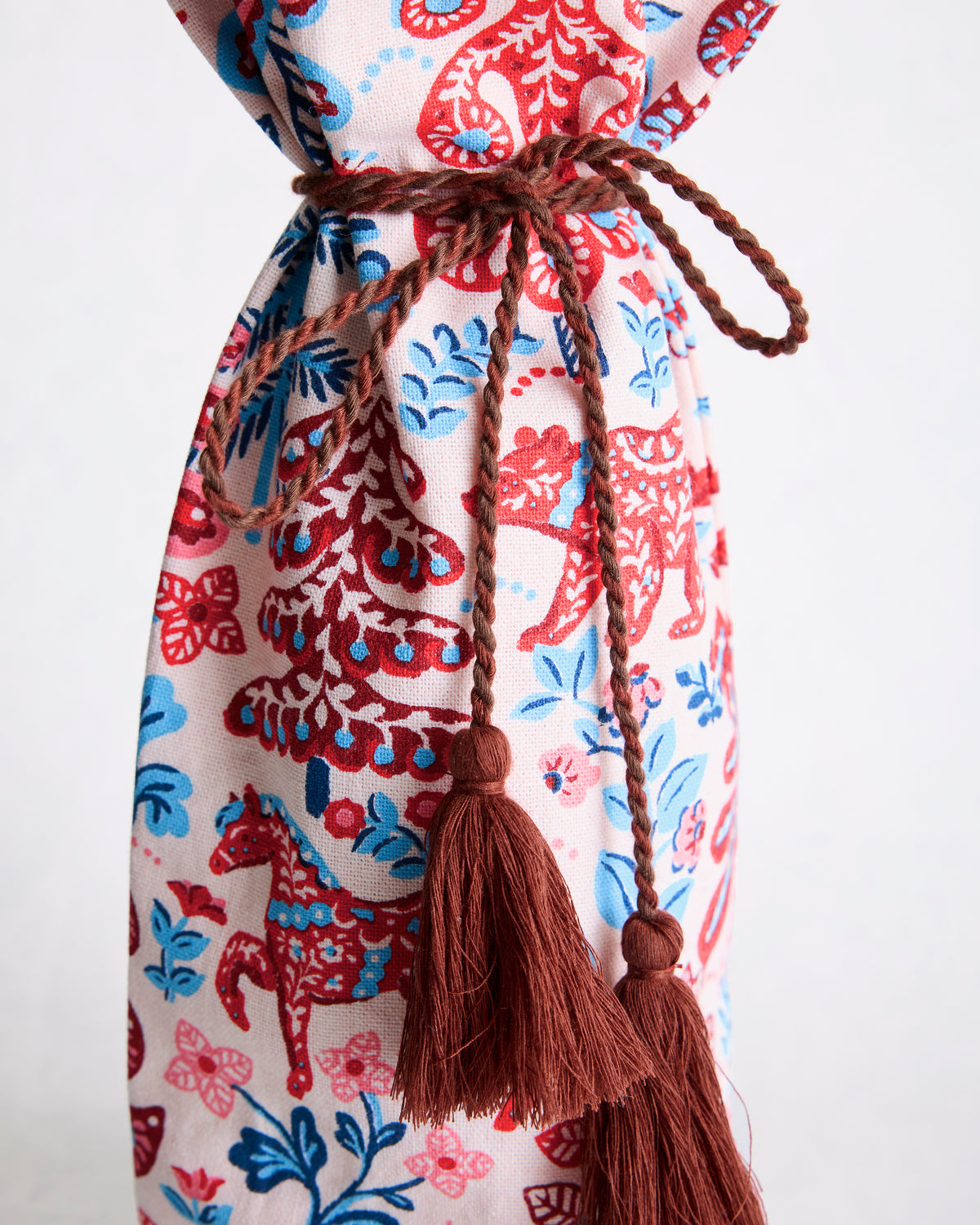 Close-up of the wine bag's brown braided drawstring and tassels over the Folklore Forest print.
