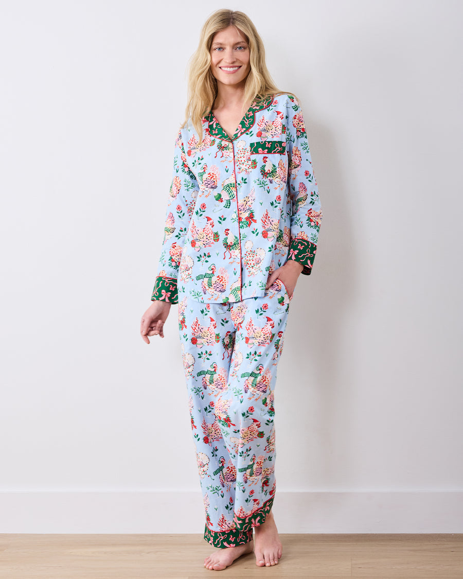 Full-length front view of a person wearing the pale blue Holiday Hens long pajama set with a button-front top and matching pants.
