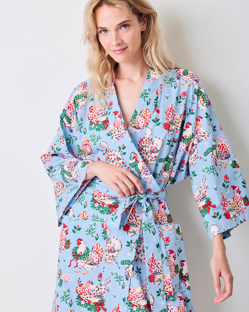 Close-up front view of the pale blue Holiday Hens robe with wide sleeves, a tied belt, and a print of hens wearing winter hats and scarves.