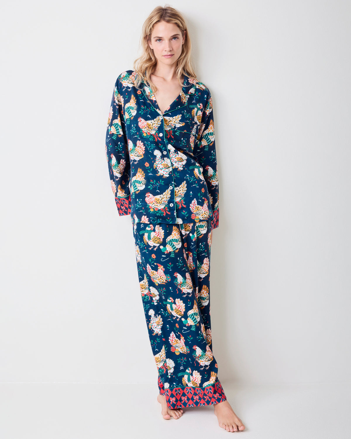 Full-length view of a model wearing a navy chicken-print tunic pajama set with a long button-front top and wide-leg pants.