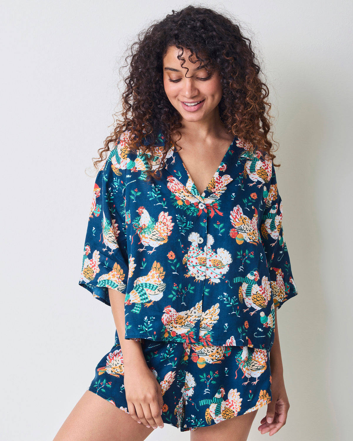 Model wearing a navy chicken-print pajama set with a relaxed short-sleeve top and curved-hem shorts.