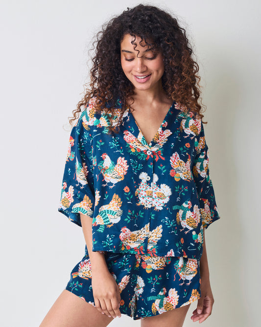 Model wearing a navy chicken-print pajama set with a relaxed short-sleeve top and curved-hem shorts.