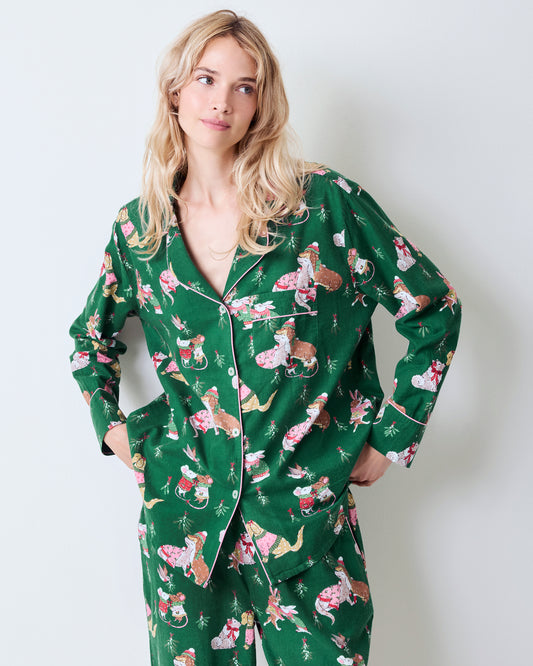 Person wearing the green Mistletoe Kiss long-sleeved pajama set with a button-front top, piping, and festive animal print.