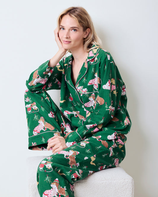 Person seated wearing the green Mistletoe Kiss flannel pajama set, showing the collared button-down top and long pants.