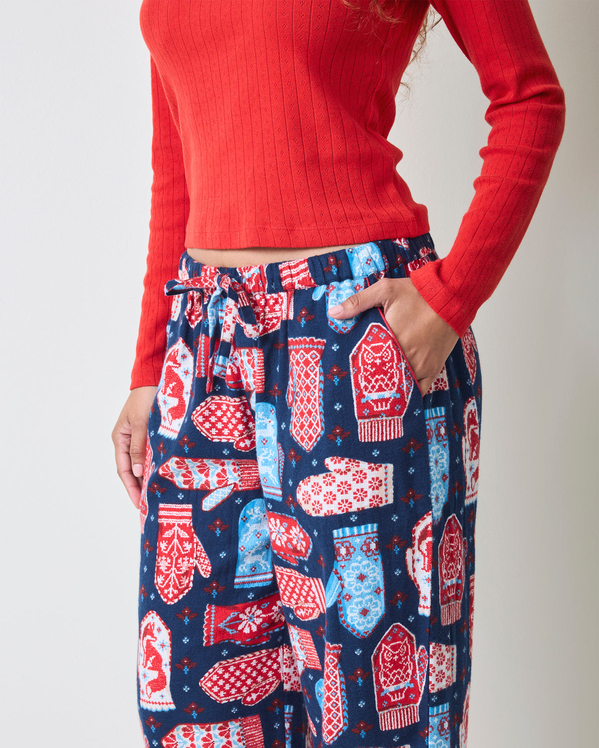 Close-up front view of blue flannel pajama pants with a mitten print, elastic waistband, drawstring, and side pocket.