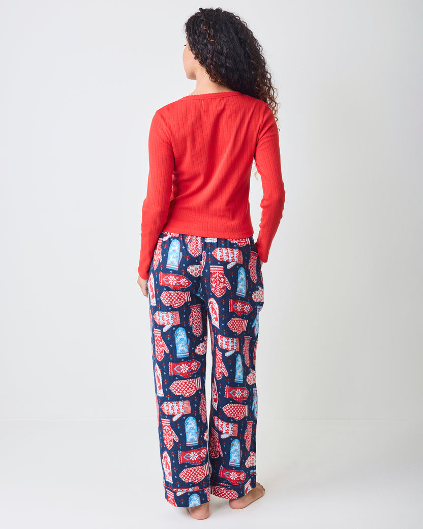 Back view of blue flannel pajama pants with a red, white, and light blue mitten print on a model.