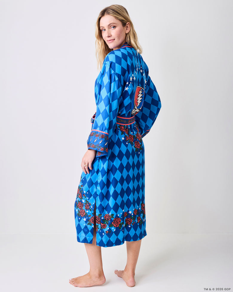 Back three-quarter view of the blue patterned robe, showing the knee-length shape, rose-and-star hem border, and back graphic.