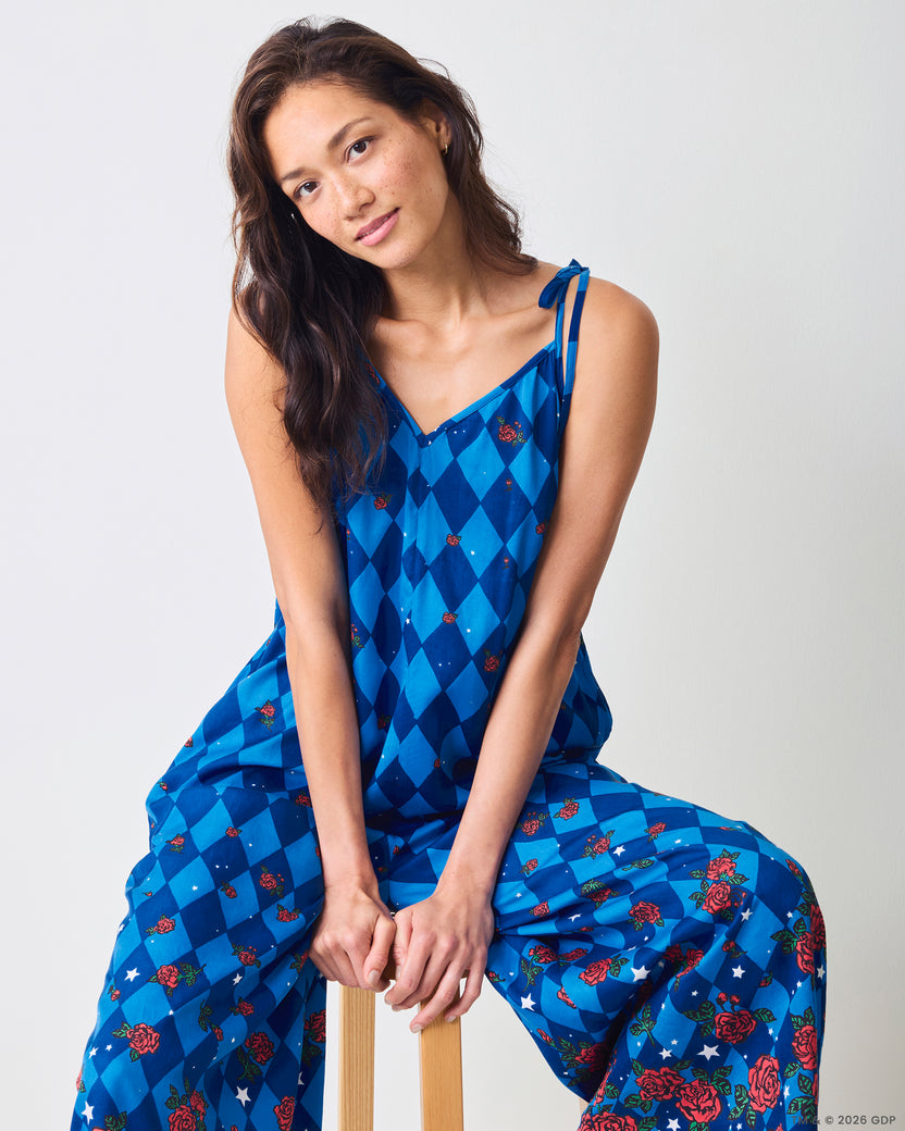 Seated view of the blue argyle-print Jaipur jumpsuit with tied shoulder straps and rose and star motifs.