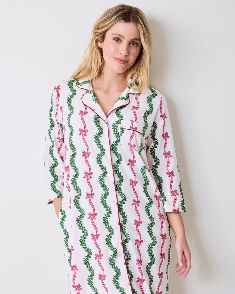 Model wearing the Ribbons & Bows sleep shirt, shown from the front with a button closure, chest pocket, three-quarter sleeves, and pink and green vertical print.
