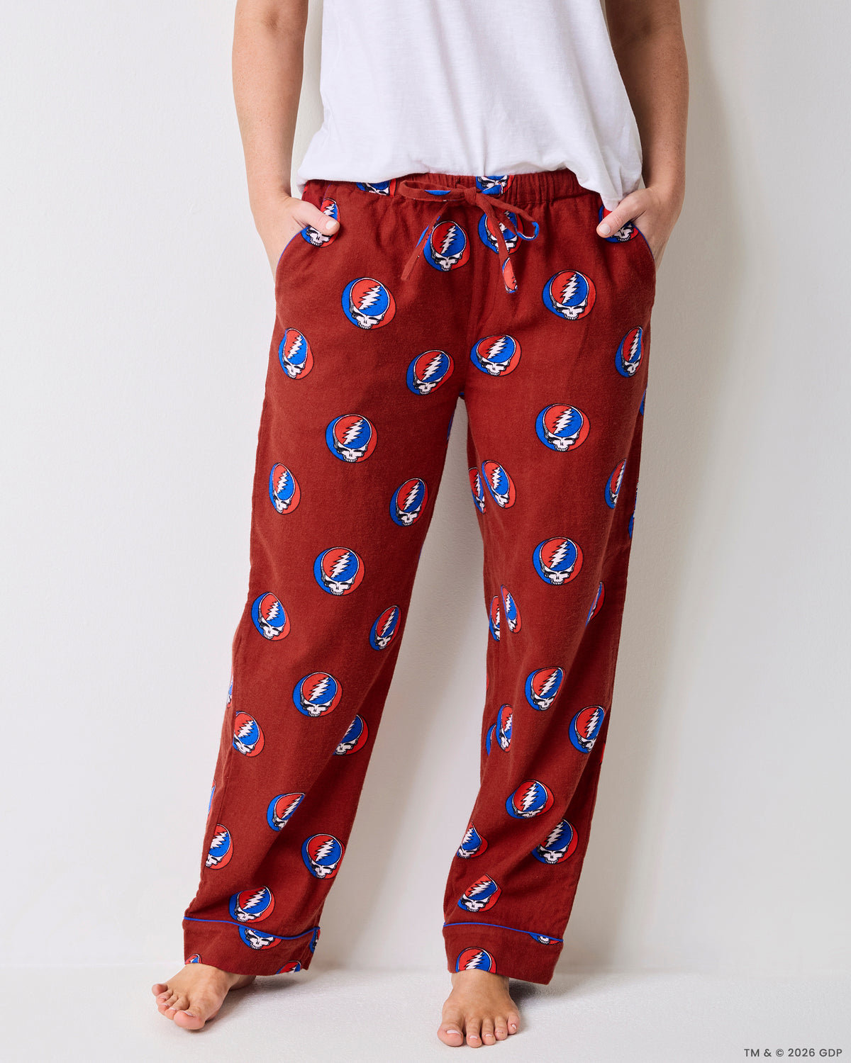 Front view of red pajama pants with an elastic drawstring waist, side pockets, and skull-and-lightning-bolt print.