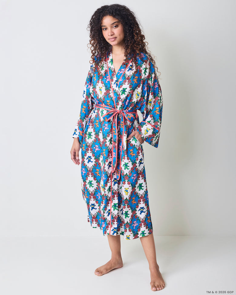 Full front view of a long robe with wide sleeves, pink trim, waist ties, and a blue-and-white bear-and-rose print.
