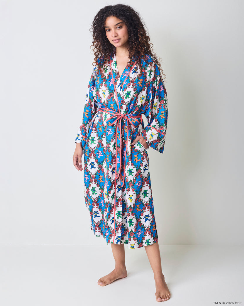 Full front view of a long robe with wide sleeves, pink trim, waist ties, and a blue-and-white bear-and-rose print.