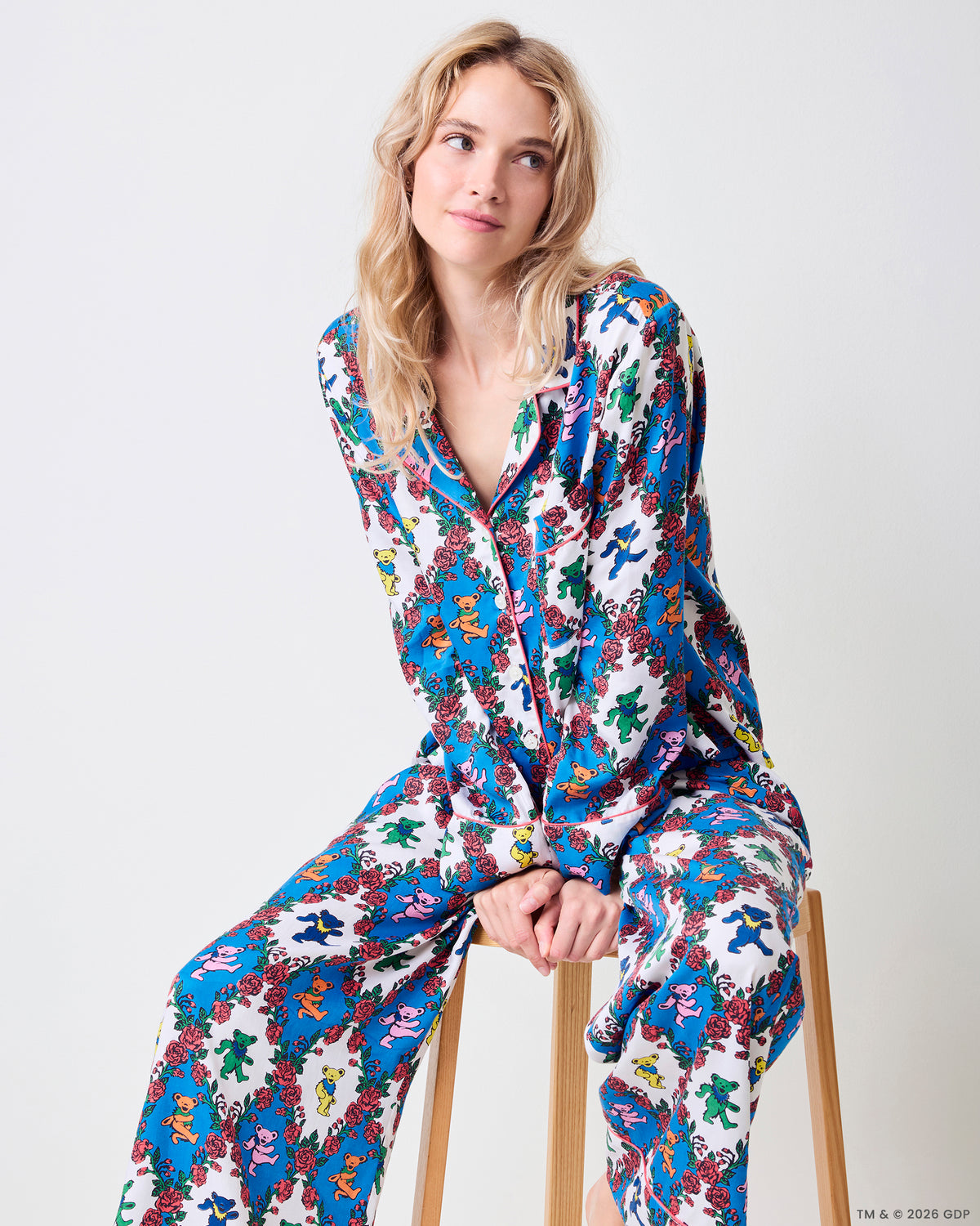 Seated full-length view of the Wandering Rose Palo Alto Soho set with a collared top and wide-leg pants in the rose and dancing-bear print.
