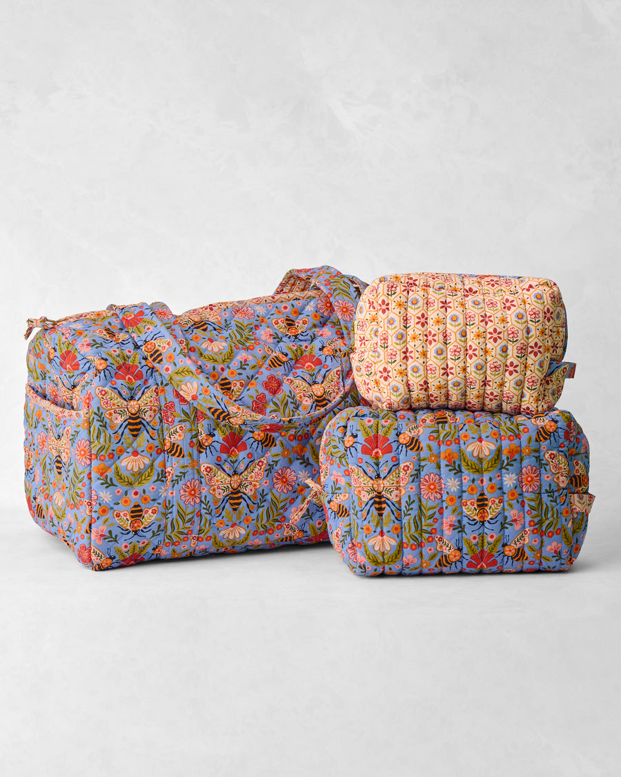 Bee Tapestry quilted duffle and two coordinating pouches, arranged together.