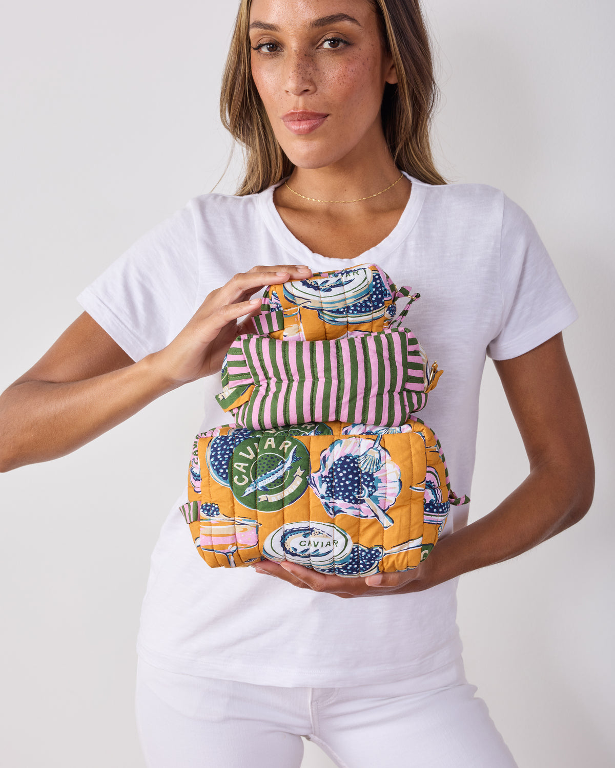 Three quilted pouches from the Champagne & Caviar set stacked vertically, showing the striped middle pouch and printed top and bottom pouches.