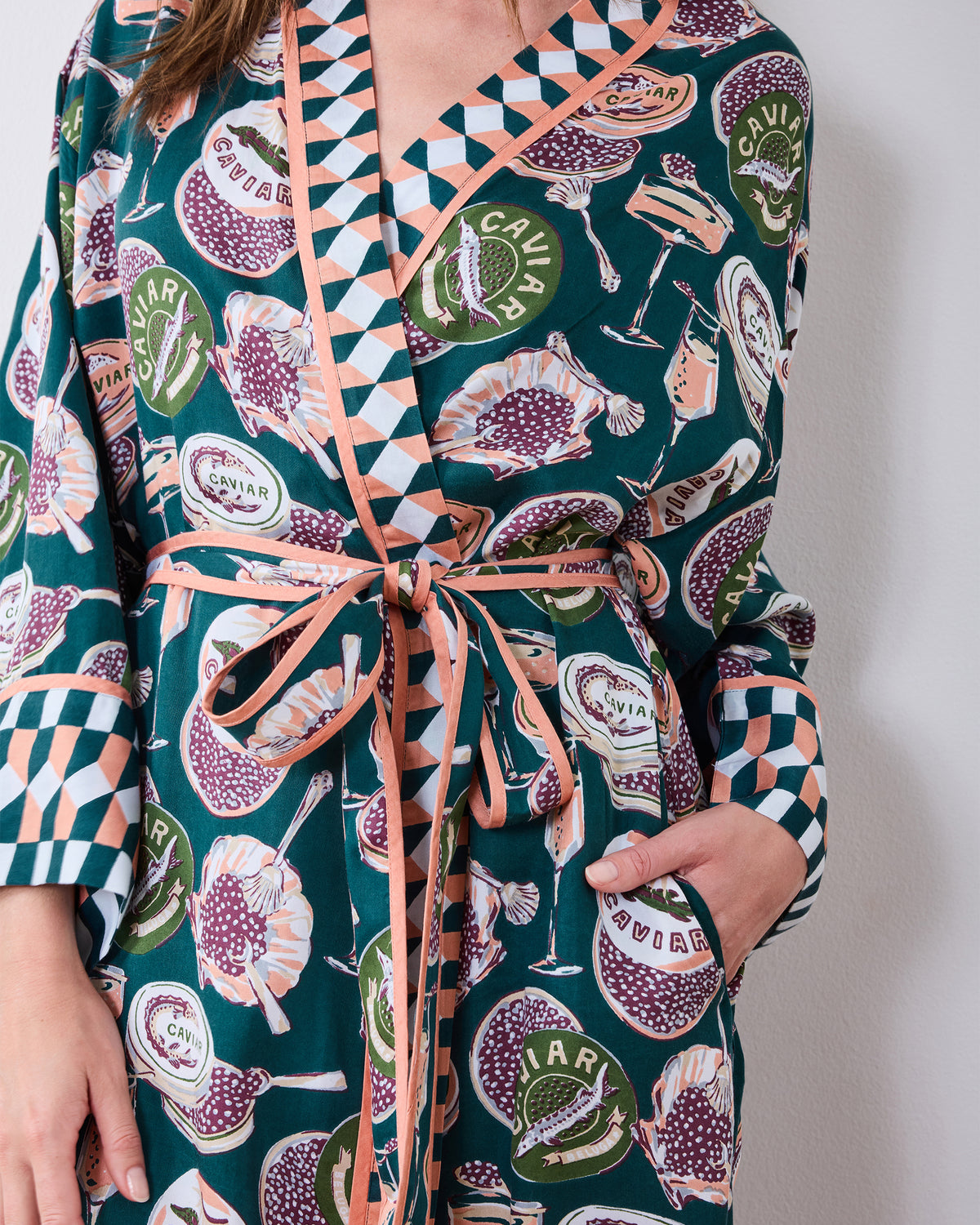 Close-up of the printed robe showing its tied waist, contrast cuff trim, and hand in a side pocket.