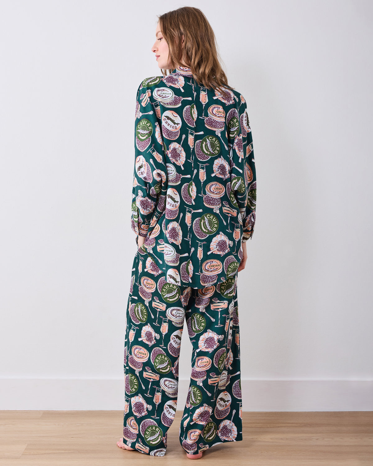 Back view of the Champagne & Caviar Stevie pajama set with a button-front top and wide-leg pants covered in caviar tins and champagne flutes.