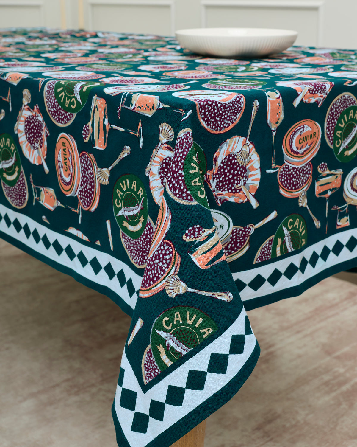 Champagne and caviar tablecloth covering a table, with a patterned border and printed caviar tins, seafood, and serving items.