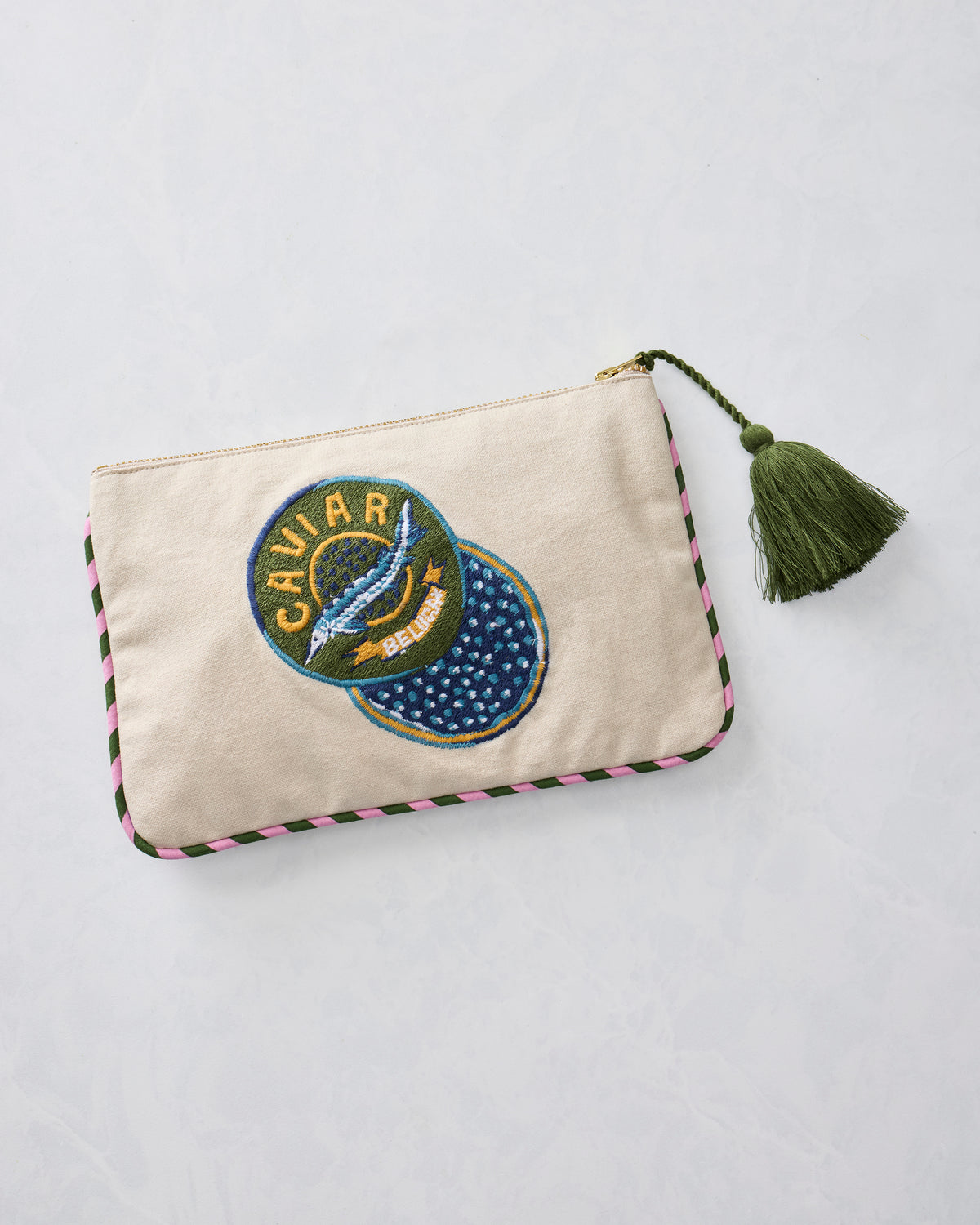 Natural canvas pouch with embroidered Caviar and Breakfast badge, gold zipper, green tassel, and pink-and-green trim.