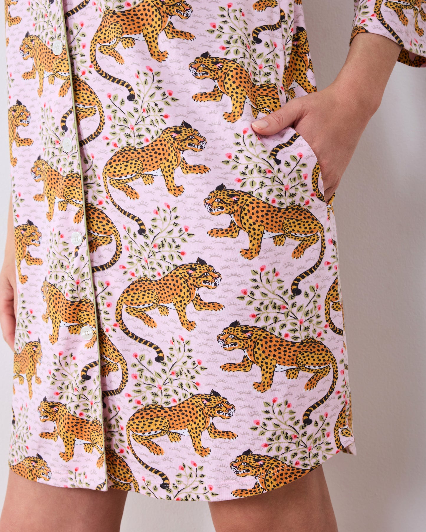 Close view of a pink button-front sleep shirt with three-quarter sleeves, a leopard-and-floral print, and side pockets.