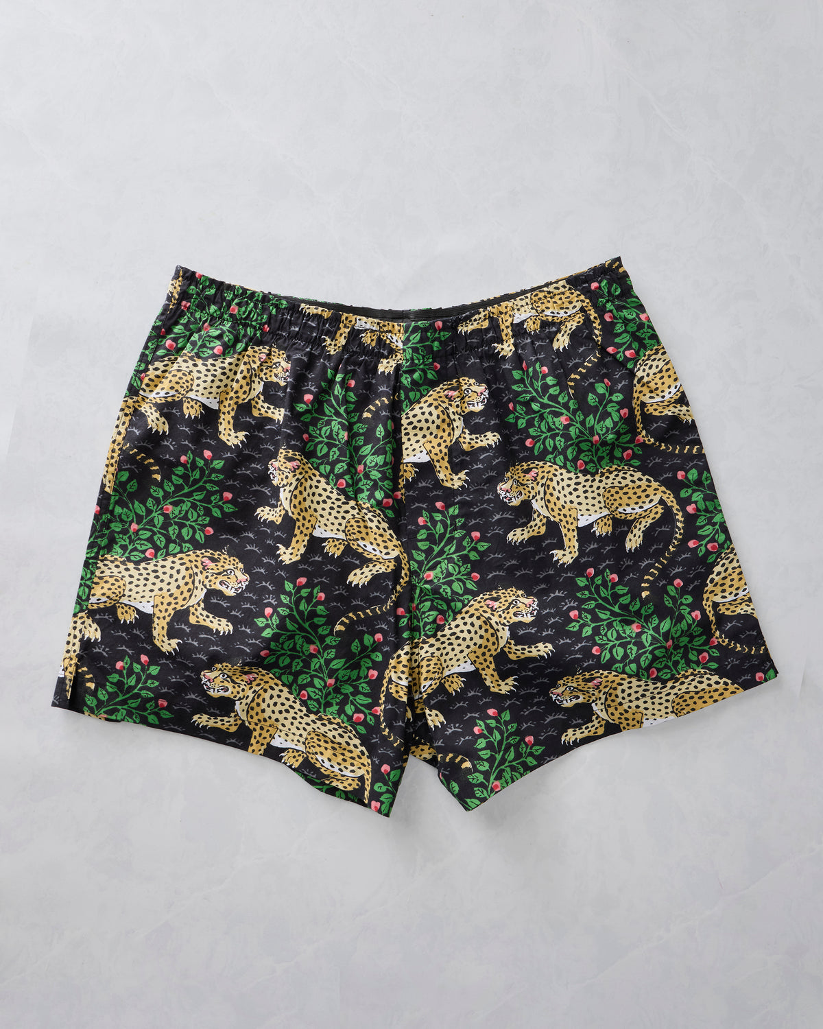 Ink boxer shorts laid flat with a spotted leopard, green foliage, and pink berry print
