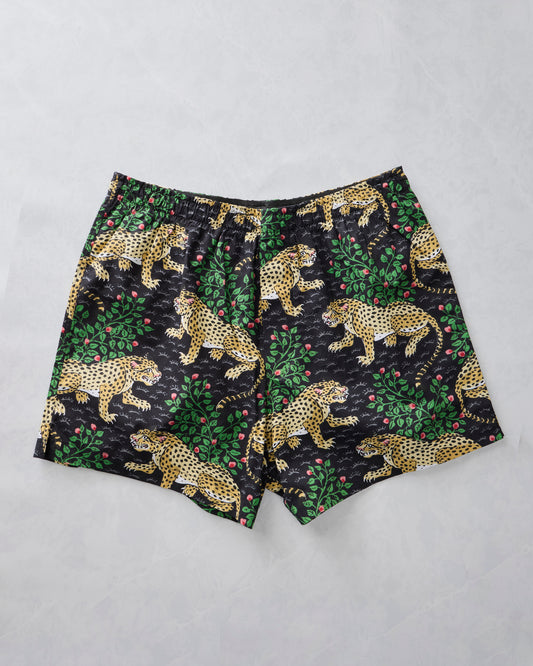 Ink boxer shorts laid flat with a spotted leopard, green foliage, and pink berry print