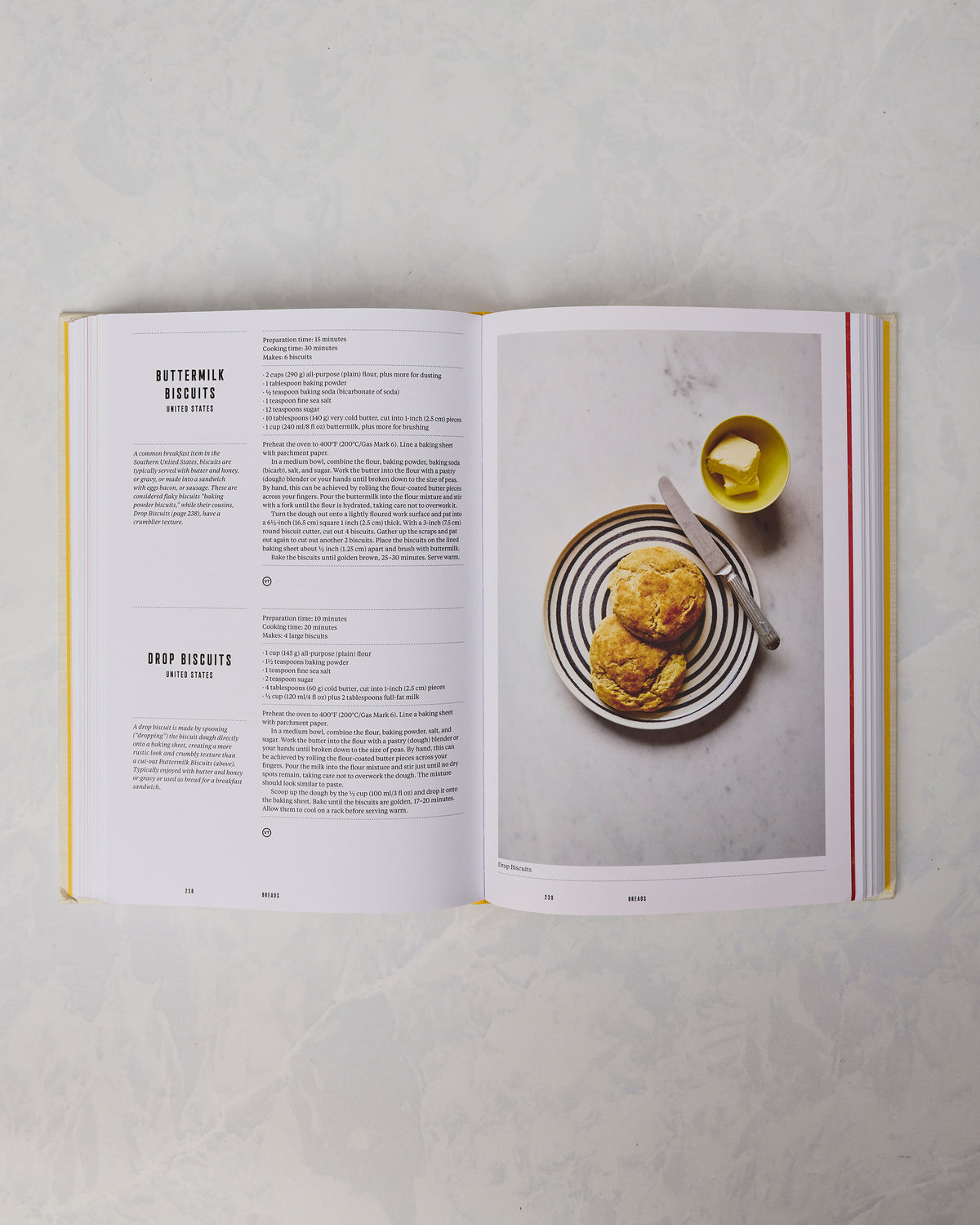 Open breakfast cookbook showing biscuit recipes on the left and a photograph of two biscuits on a striped plate with butter on the right.