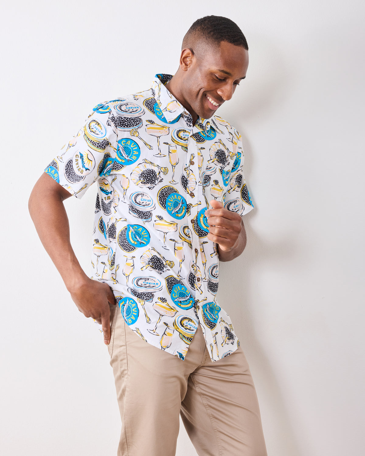 Front three-quarter view of the Champagne & Caviar Leo Shirt worn with trousers, showing its short sleeves and all-over caviar and champagne print.