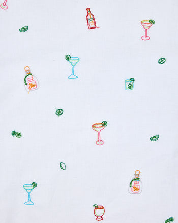 White fabric swatch with repeated colorful embroidered cocktail glasses, bottles, citrus slices, and drink illustrations.