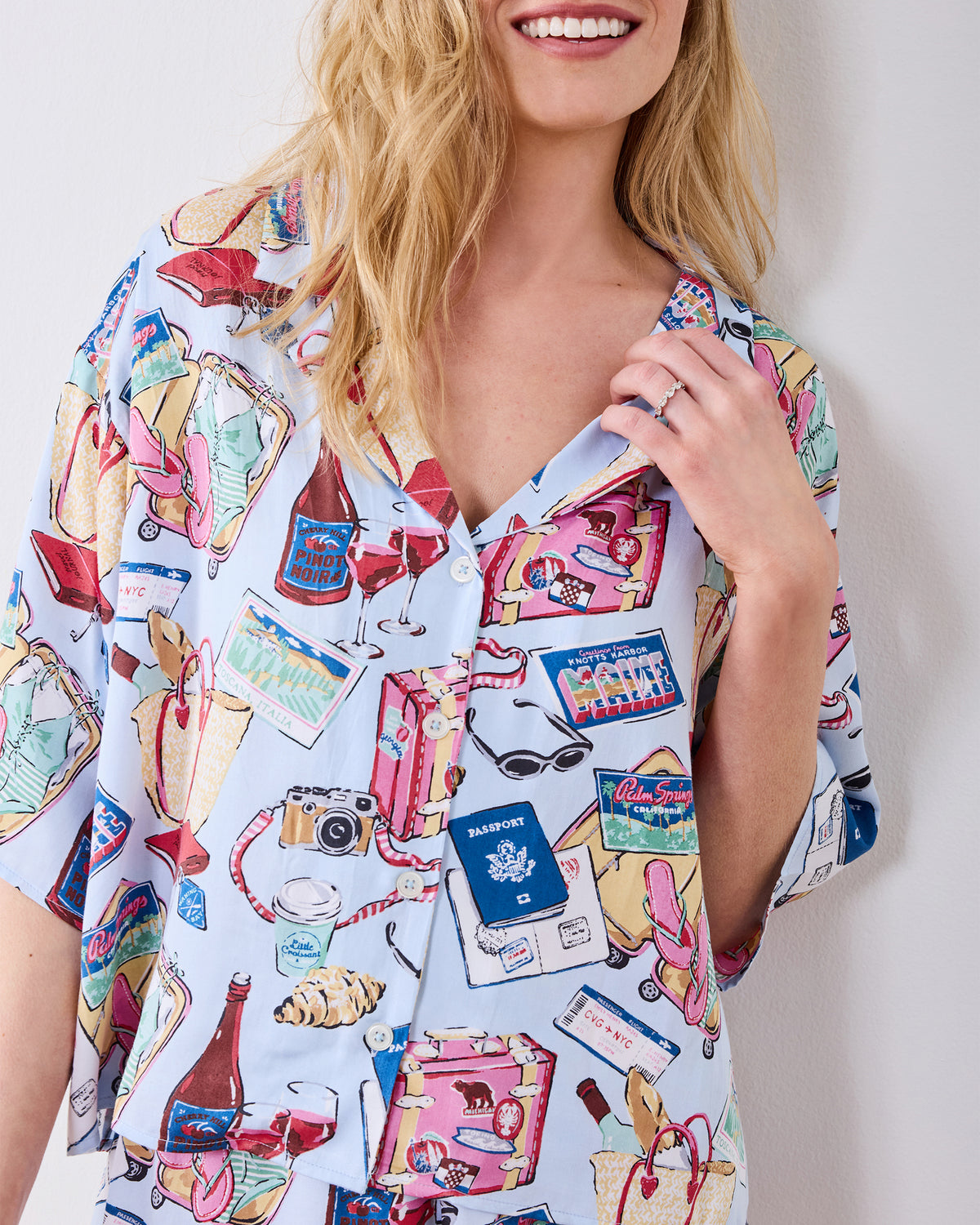 Close-up of the pale blue printed pajama top showing its collar, buttons, and travel-themed illustrations.