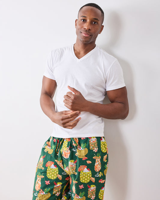 Model wearing green Paradise Punch pajama pants with a tropical drink print and white T-shirt