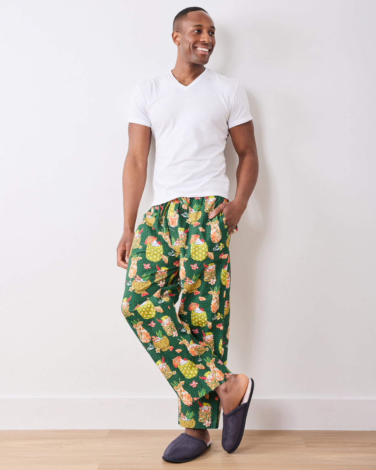 Full-length front view of a model wearing green Paradise Punch pajama pants with slippers
