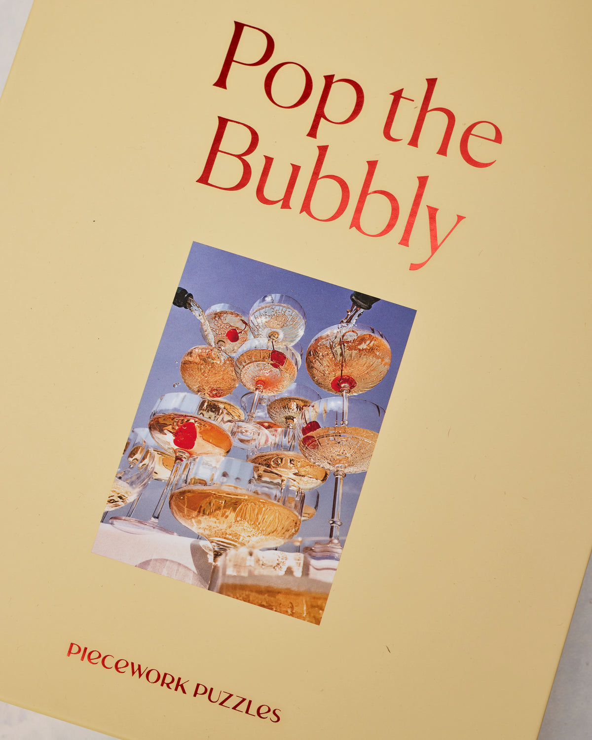 Angled close-up of the Pop the Bubbly puzzle box with champagne coupe artwork.