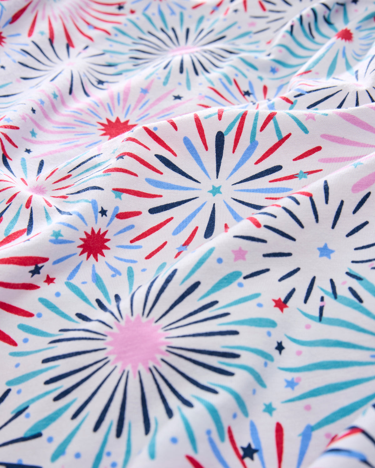 Close-up of the white pajama print with red, pink, blue, and navy fireworks and stars