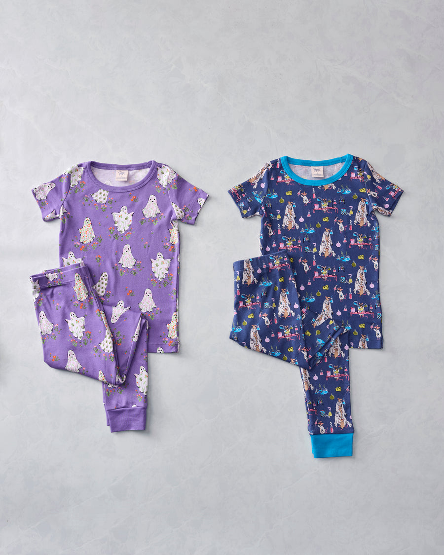 Two children's short-sleeved pajama sets displayed flat: a purple ghost-print set and a navy monster-print set.
