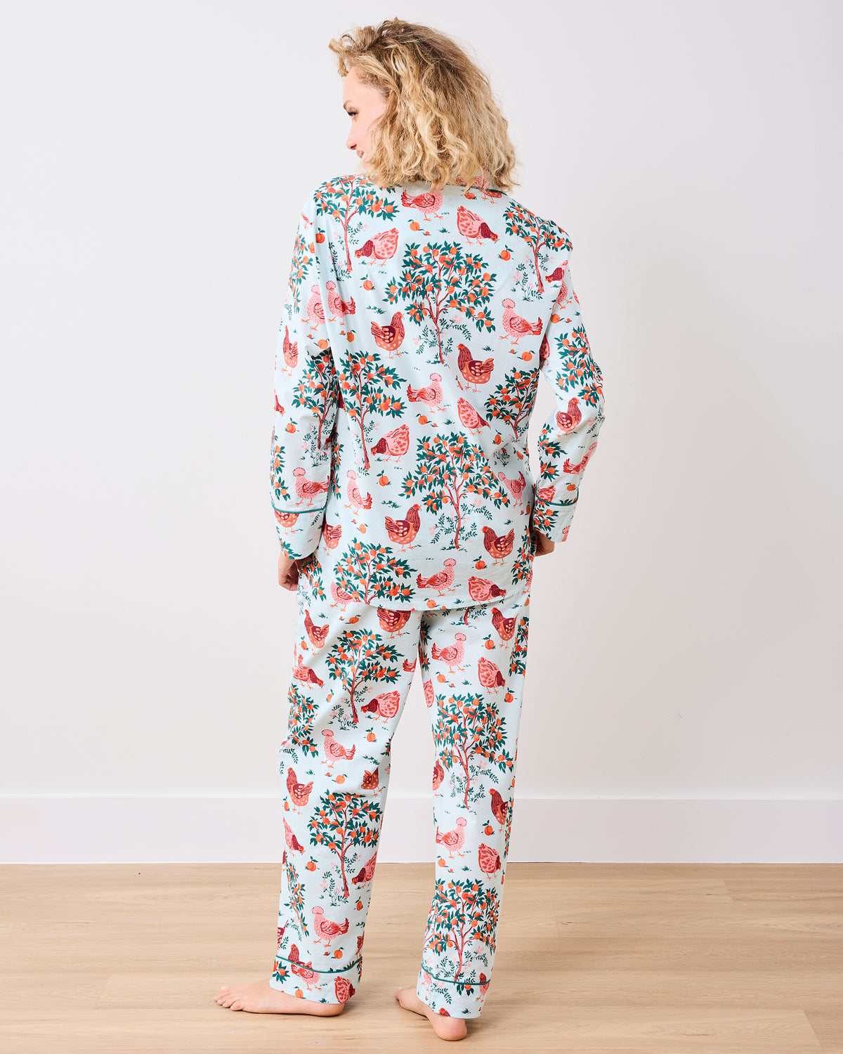 Back view of the long pajama set with a chicken and fruit-tree print on a light blue background