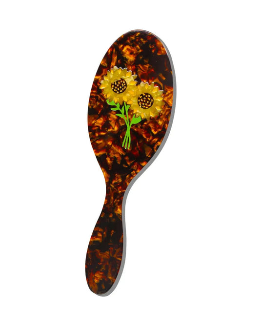Brown tortoiseshell-pattern hairbrush decorated with two yellow sunflower ornaments.