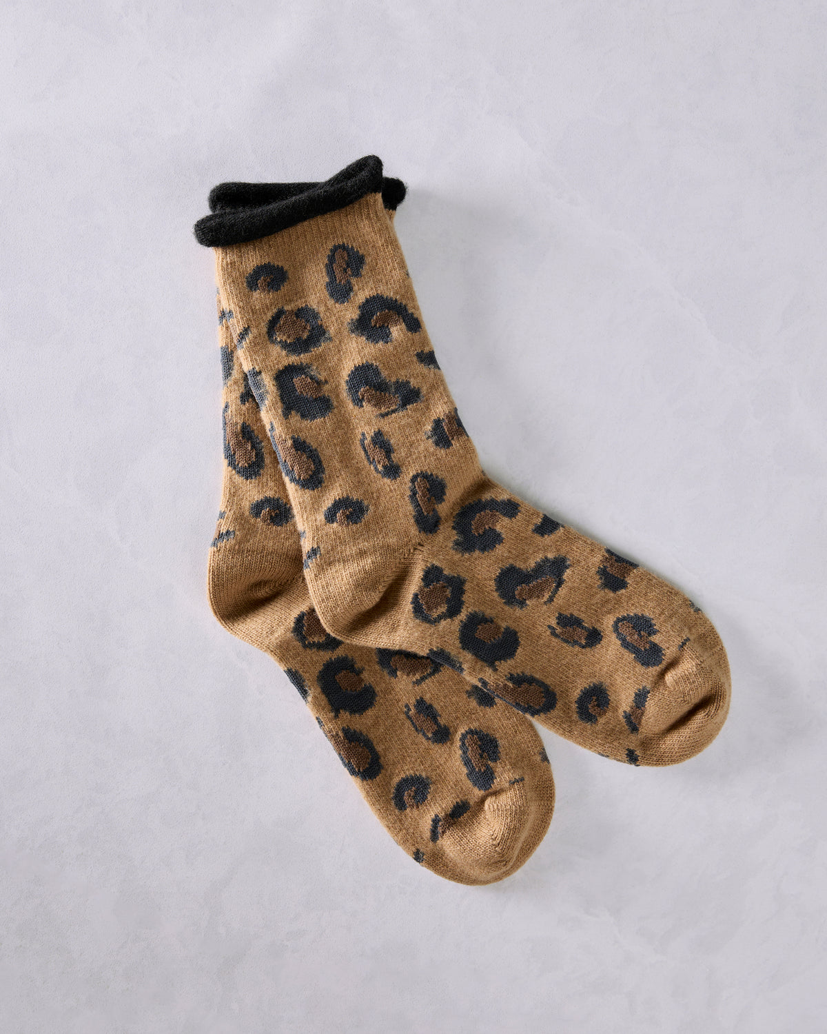 Pair of camel crew socks with black leopard-like spots and black cuffs, shown overlapping.