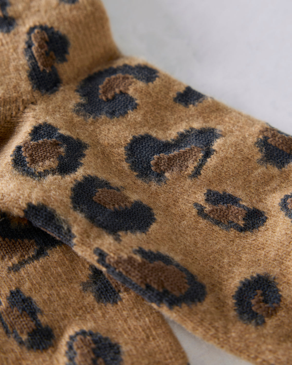 Close-up of the camel socks showing the textured knit and black-and-brown spot pattern.