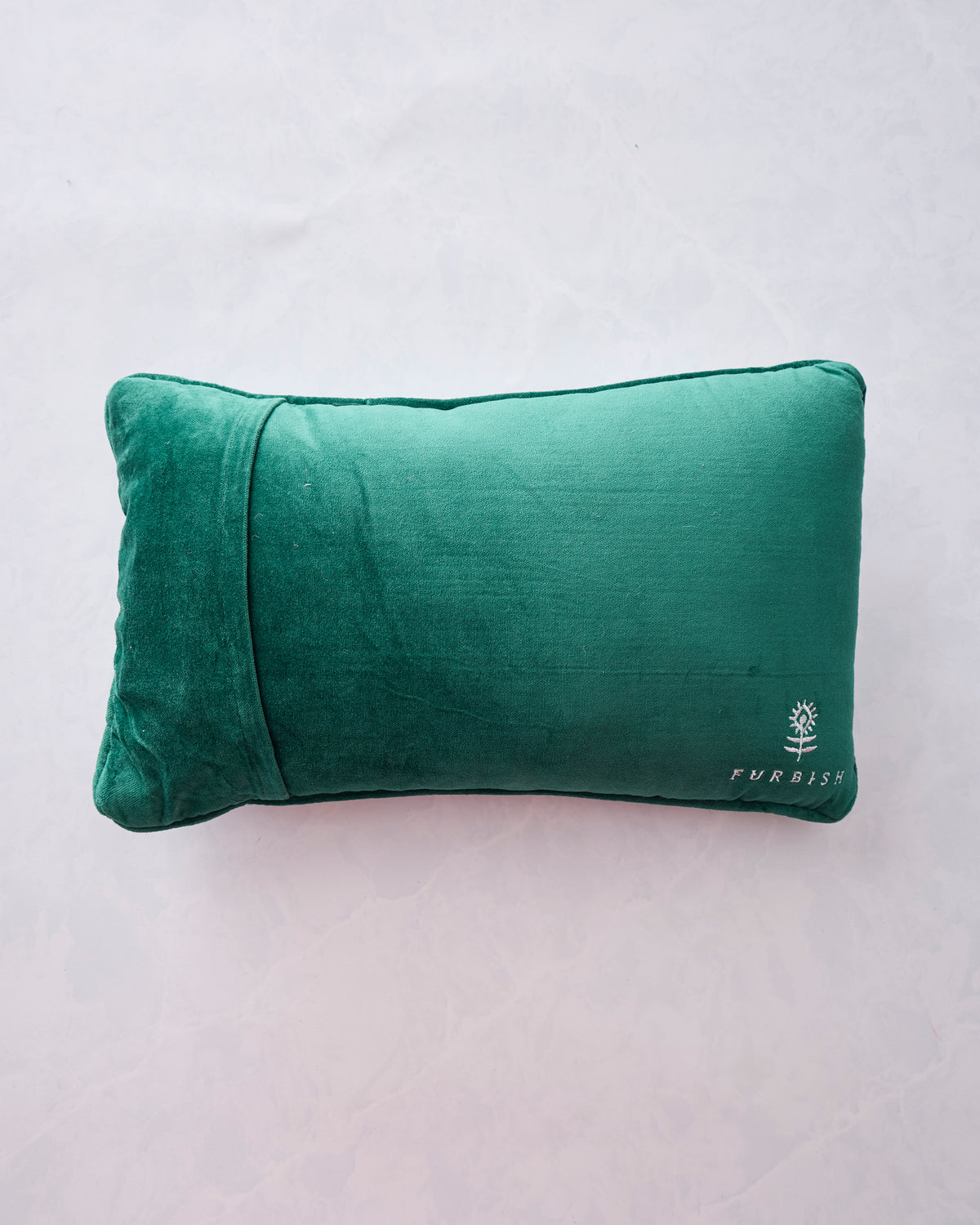 Back view of a green rectangular pillow with a velvet-like backing and a small Furbish logo near the lower right.