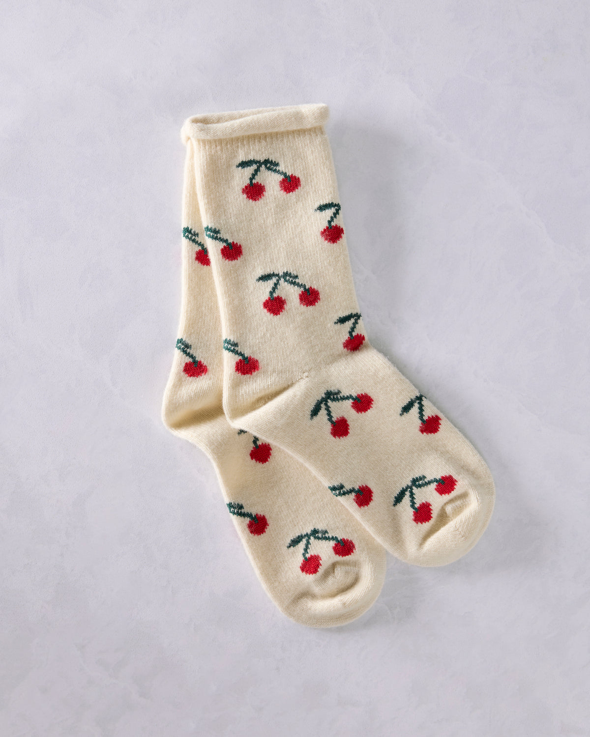 Pair of ivory crew socks with repeated red cherry and green stem motifs.