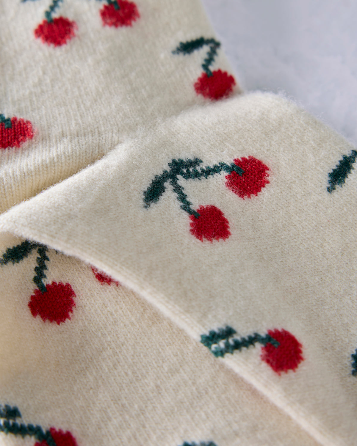 Close-up of the ivory socks showing the red cherry and green stem pattern.