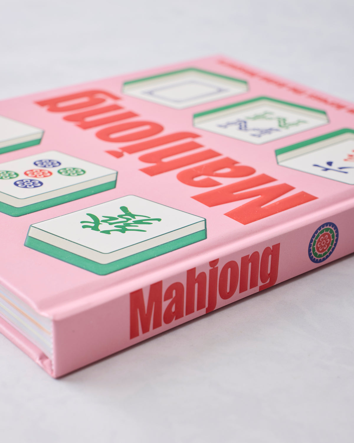 Close angled view of the pink Mahjong book cover showing illustrated tiles and the title along the spine.