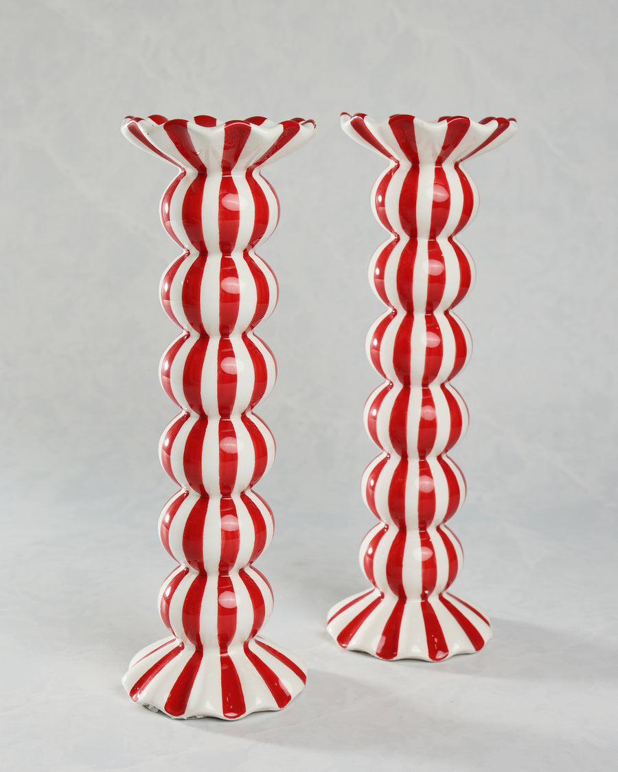 Two red-and-white vertically striped ruffle candle holders standing side by side.