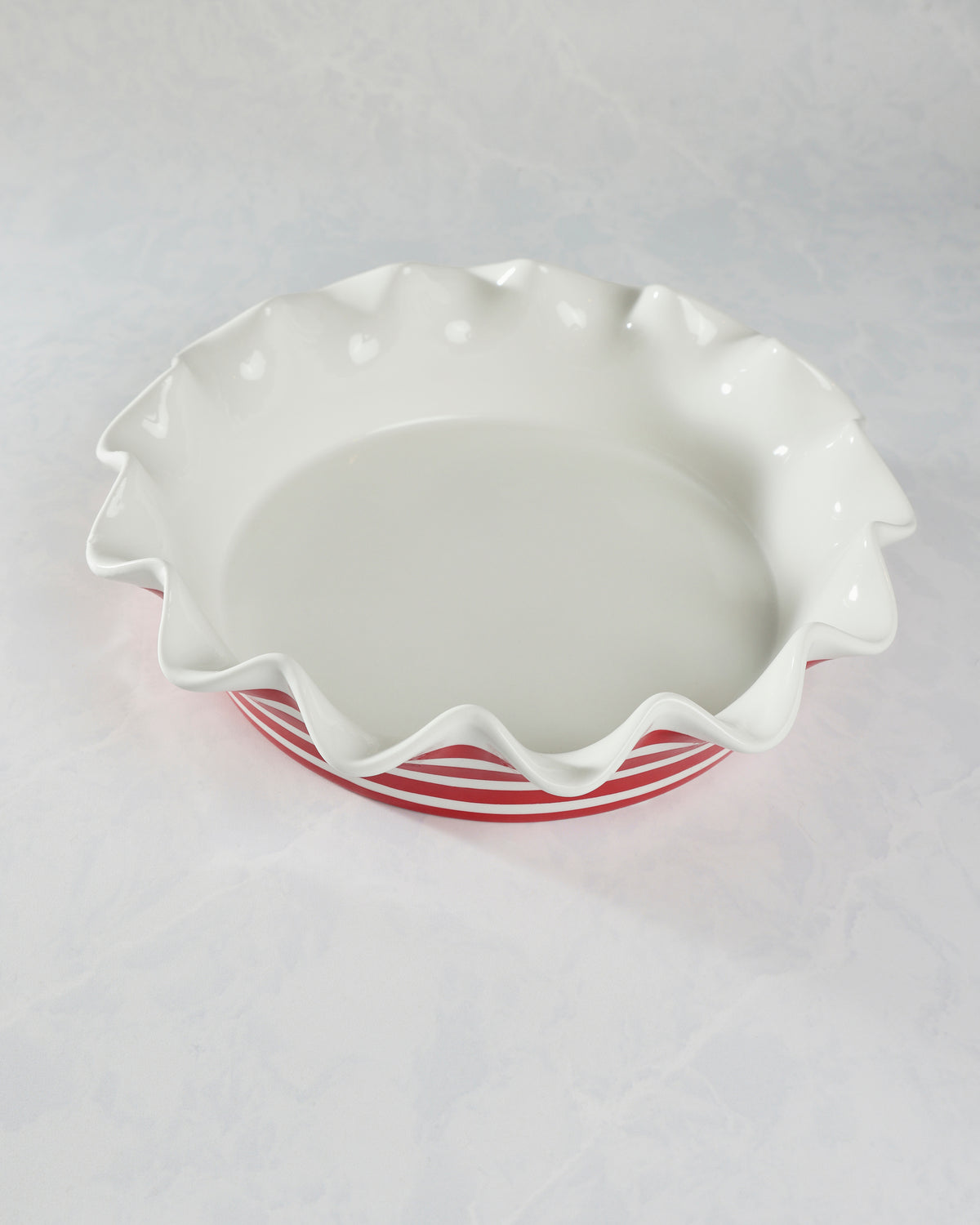 Red-and-white striped ceramic ruffle pie dish viewed from above, showing the white interior.